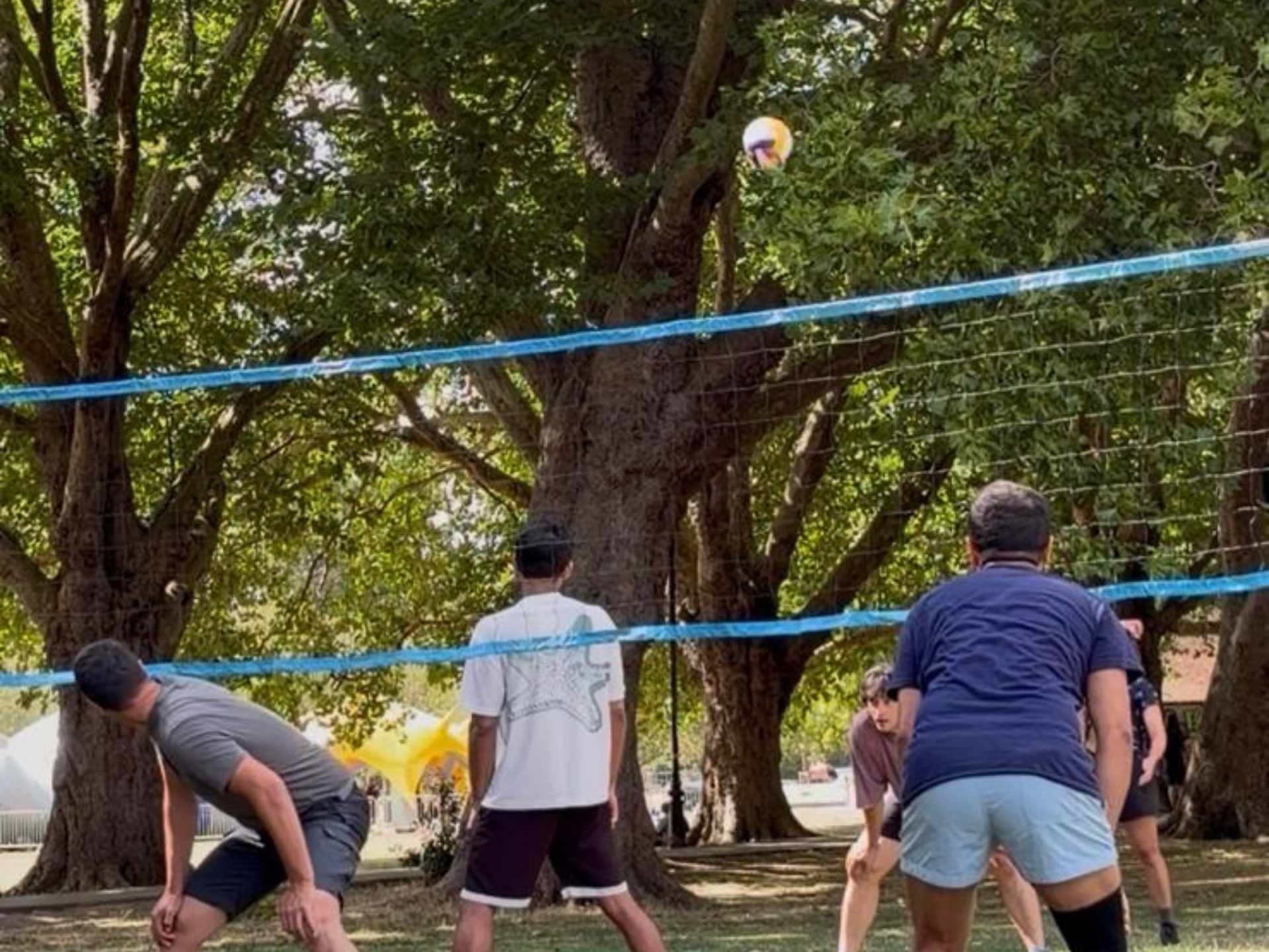 A group of young adults playing casual outdoor volleyball in the park